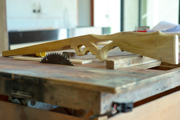 Selective focus on wooden toy in gun shape on electrical cutting machine at house under construction site.