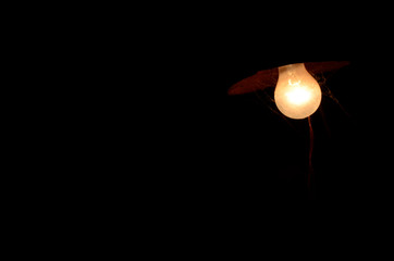 Old and dirty lamp lit on black background