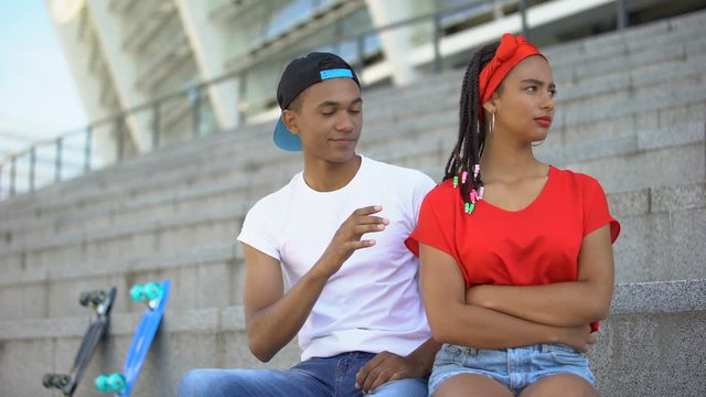 Multi-ethnic girl offended at her boyfriend, ignoring his attempts to make peace