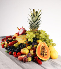 Tropical fruits background, many colorful ripe fruits with strawberries, grapes and cherries on wooden background