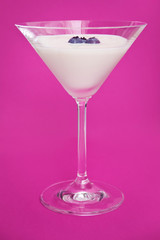 Vertical photo of fresh yogurt with blueberries in a glass on pink background.