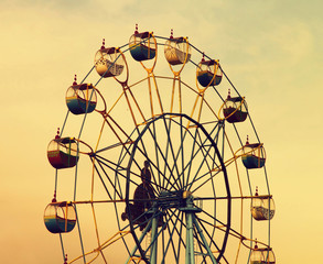 Ferris wheel on evening cloudy sky background.