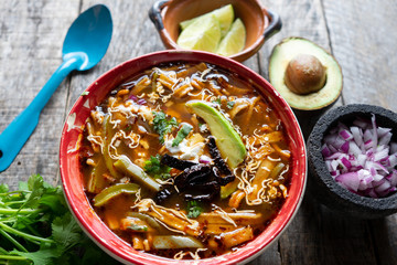 Mexican tortilla soup on wooden background