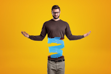 Young man in casual clothes cut in half with blue liquid spiral inside on yellow background