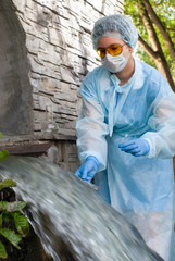 female sanitary inspector takes a sample of water from urban wastewater