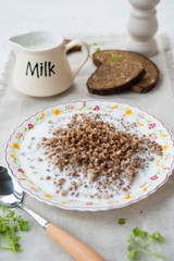 Traditional Russian food. Buckwheat porridge with milk and black bread on the table. Horizontal orientation.
