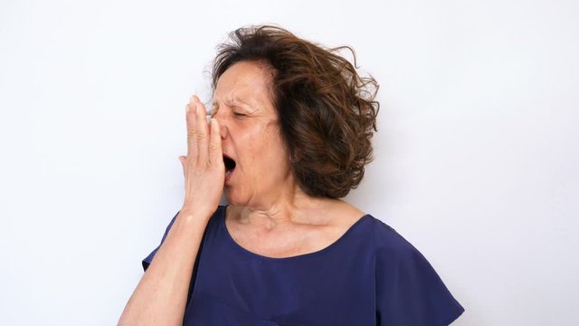 Mature woman yawning isolated on white background. Filmed in 4K