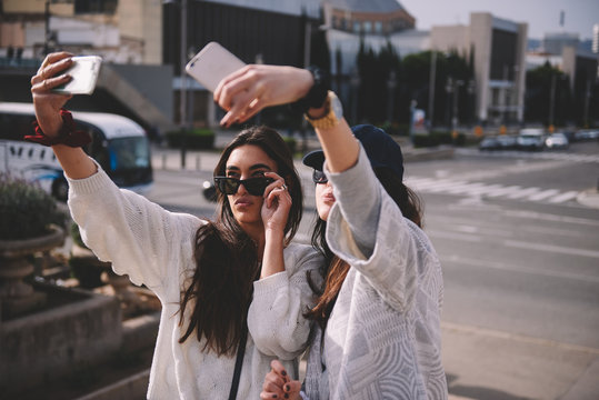 two young woman making a selfie with their smartphones
