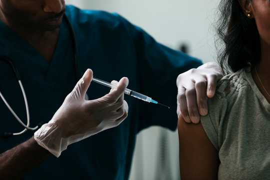 Close up of doctor giving vaccine shot to woman
