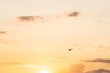 Beautiful sunset. Yellow and orange, warm colors. Clouds are visible in the sky. In the foreground you can see a helicopter. Travel, vacation and holidays. Background with free space and empty place.