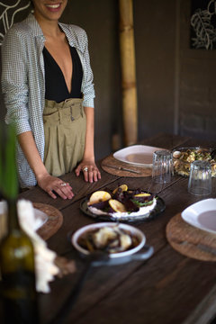Woman standing at table of food, face cropped