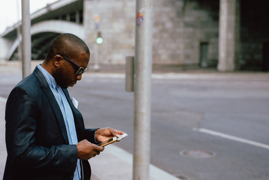 Black man dialing number on smartphone on street