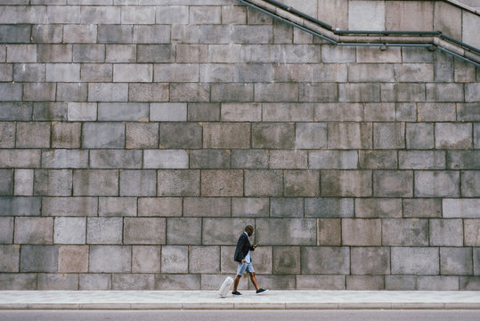Black man with suitcase near brick wall