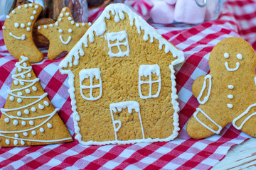Obraz premium Traditional homemade gingerbread cookies on red rustic background with imitation snow,close up,Christmas concept,gingerbread house and gingerbread man