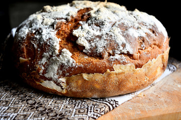 Homemade bread lies on a kitchen board in a folk, national napkin kitchen, on a wooden table.