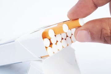 Caucasian man hand catching a cigarette isolated on white background. Cigarette taken out of the box. Tobacco can cause diseases in the organism.