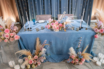 Blue tablecloth, plates and candlesticks with candles. Luxury dinner Banquet in the restaurant. Beautiful and exquisite decoration of the wedding celebration.