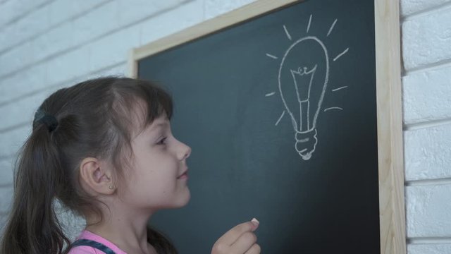 The child draws a light bulb. A little girl with a painted spaceship dreams of becoming an astronaut.
