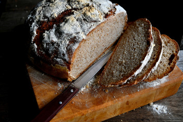 Sliced homemade bread, lies on the kitchen board in the kitchen, on a wooden table.