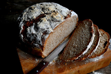 Sliced homemade bread, lies on the kitchen board in the kitchen, on a wooden table.