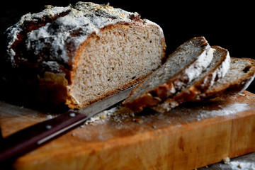 Sliced homemade bread, lies on the kitchen board in the kitchen, on a wooden table.
