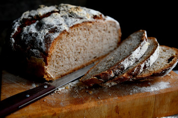 Sliced homemade bread, lies on the kitchen board in the kitchen, on a wooden table.