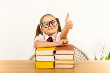 little girl with a lot of closed books gesturing thumb up