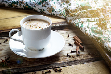 Indian masala chai tea. Spiced tea with milk on dark wooden table. Selective focus, horizontal with copy space.Sunlight.
