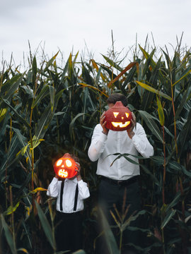 Man and boy standing with Halloween pumpkins near face