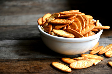 Cracker cookies in a white ceramic bowl on a wooden table.Cracker cookies in a white ceramic bowl on a wooden table.