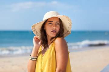 Portrait fashion of pretty young woman with straw hat on a beach in Summer. Happy Smiling girl..