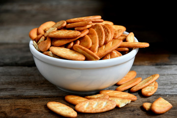Cracker cookies in a white ceramic bowl on a wooden table.Cracker cookies in a white ceramic bowl on a wooden table.