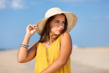 Portrait fashion of pretty young woman with straw hat on a beach in Summer. Happy Smiling girl..