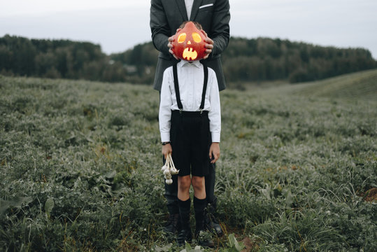 Man and boy standing in field with Halloween pumpkin