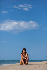 Calm young woman sitting alone on a sand beach. Relaxing and  harmony concept..