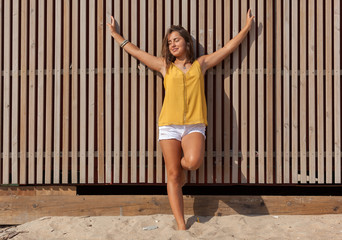 Pretty young woman leaning against a wooden fence..Happy girl enjoying freedom in the sun at the...