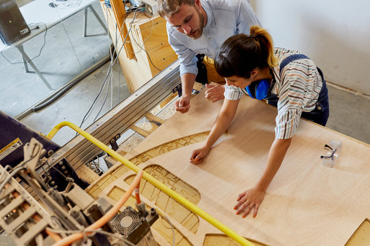 Teacher Guiding Student In Using Laser Cutter
