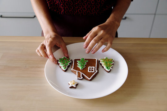 Crop woman arranging gingerbread cookies