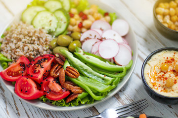 Hummus platter with assorted snacks. Hummus in bowl, vegetables sticks, chickpeas, olives. Plate with Middle Eastern/Mediterranean meze. Party/finger food. Top view. Vegetables, hummus dip,copy space