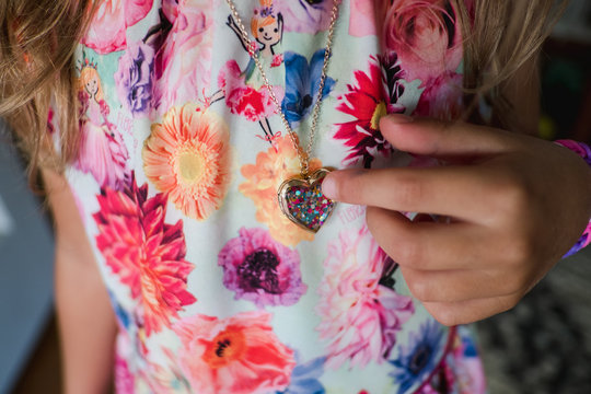 little girl looks at locket necklace