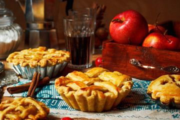 Obraz na płótnie Canvas Mini homemade apple pies on rustic background with coffee,cinnamon sticks,apples,vintage towel