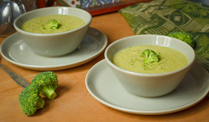 Fresh Broccoli cream soup on two gray ceramic bowl on plate with spoon on marble background,vegetarian food,healthy concept
