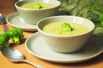 Fresh Broccoli cream soup on two gray ceramic bowl on plate with spoon on marble background,vegetarian food,healthy concept