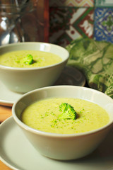Fresh Broccoli cream soup on two gray ceramic bowl on plate with spoon on marble background,vegetarian food,healthy concept