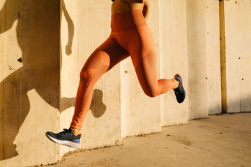 Crop sportswoman running above ground