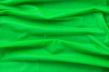 Background in the form of material from bright green nylon with horizontal folds, top view