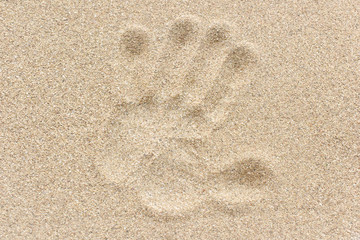 Huella de mano en arena de playa.