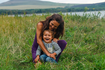 Naklejka na ściany i meble Happy family having fun on vacation. happy and harmonious family in the fresh air. mother and son laughing and playing in the summer on the nature. Happiness and joy, fun.