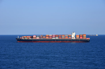 Cargo container ship loaded with containers during her voyage through the ocean. 