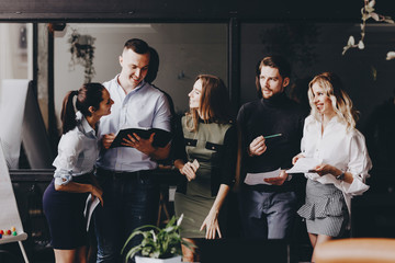 Young team of colleagues works with documents and discuss the project in a stylish modern office. Work process in the office.